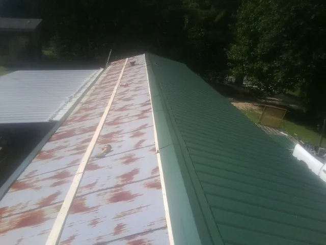 Old rusted panels beside newly installed green metal roofing — Wind Damage Roof Repair by Roofing Brothers in Greencastle