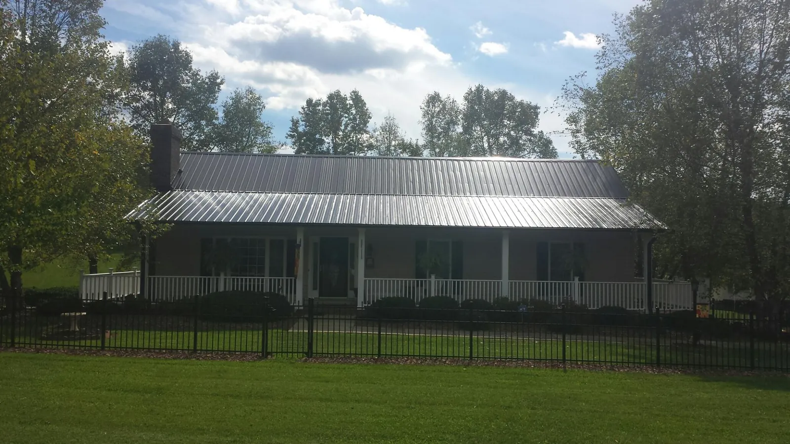 Gray metal roof on a brick ranch with a full width front porch — Gutter Guard Installation work by our crew in Greencastle
